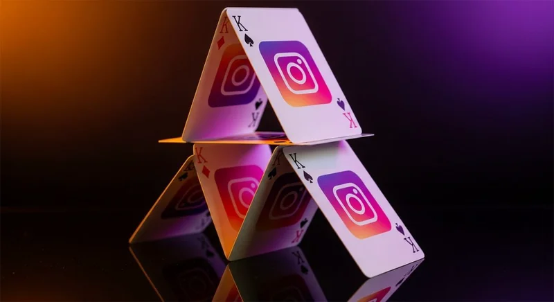 Casa de naipes con logos de Instagram sobre cristal oscuro