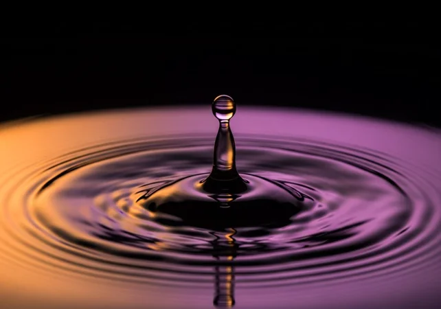 una única gota de agua en el momento exacto del impacto sobre una superficie de agua perfectamente quieta